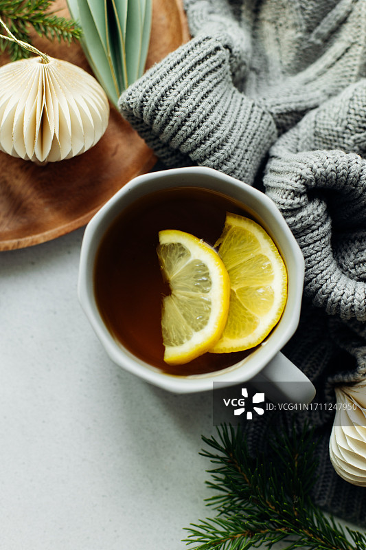 冬季静物画。温馨的构图，一杯柠檬茶，温暖的毛衣和餐桌上的节日装饰图片素材