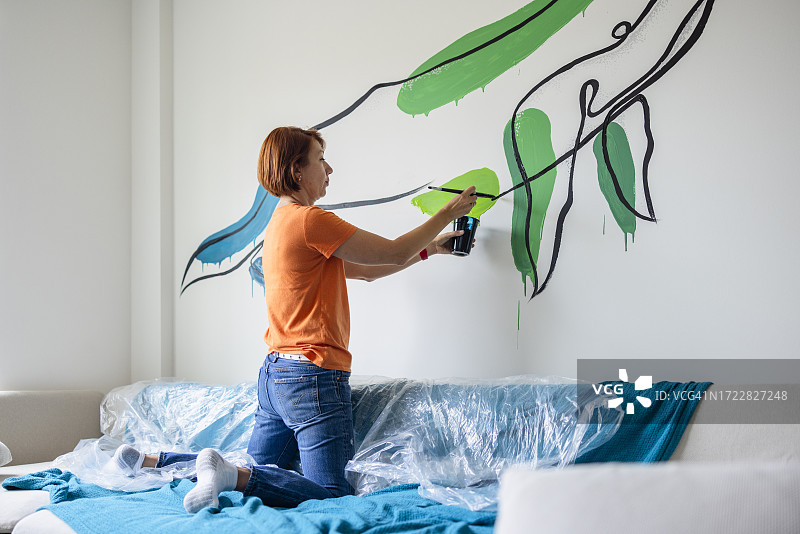 鲸鱼壁画在艺术家的手中成形:早上，红头发的女人，室内设计师在墙上画鲸鱼图片素材