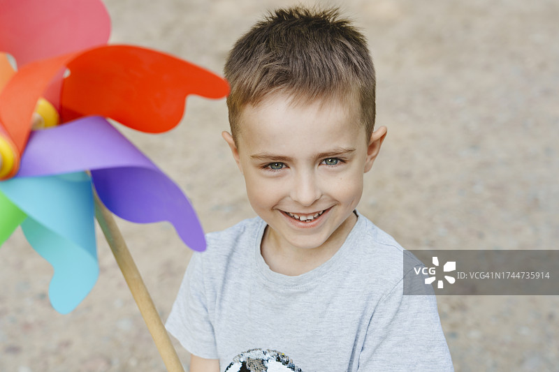 微笑的男孩带着五颜六色的彩虹风车玩具图片素材