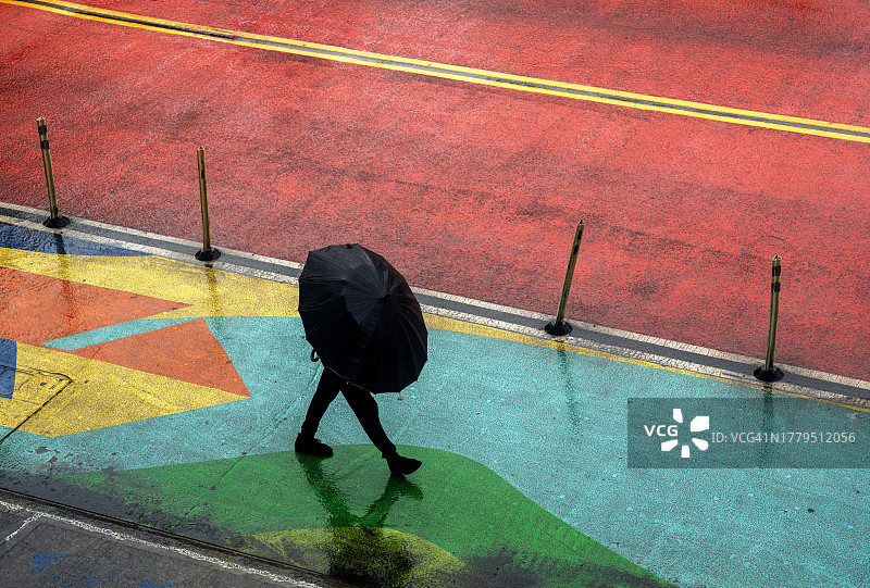 一个无法辨认的男人在纽约的雨中走在街上，用一把大伞遮住自己的身体图片素材