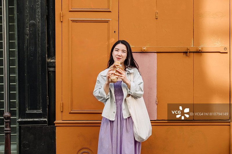 愉快的亚洲妇女在巴黎旅行时享受午餐休息和街头小吃。图片素材