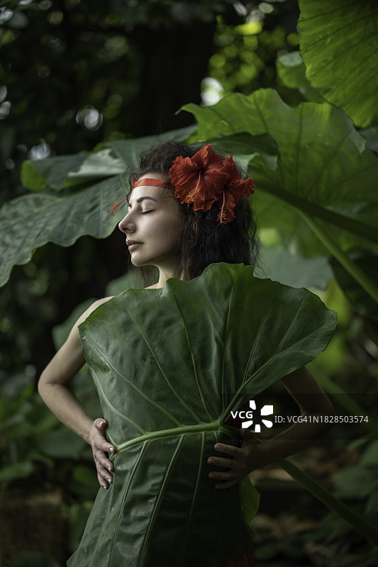 丛林中一个热带女人裹在一片大叶子里的肖像图片素材