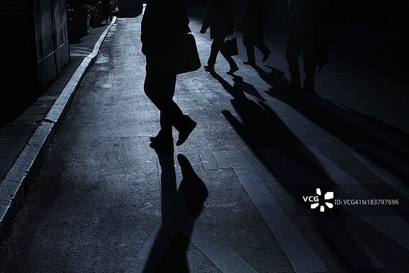 一群带着公文包的男人穿过街道的夜晚阴影图片素材