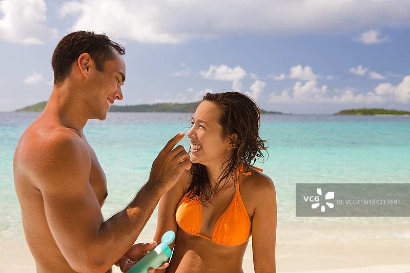 一个男人在海滩上给一个女人的鼻子涂润肤水图片素材