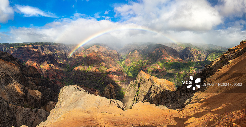 彩虹和薄雾在夏威夷雄伟多彩的山脉和山谷上移动的全景图片素材