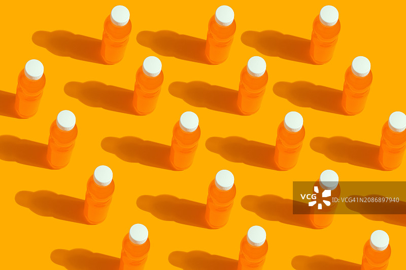 黄色背景上的橙汁塑料瓶马赛克图案图片素材