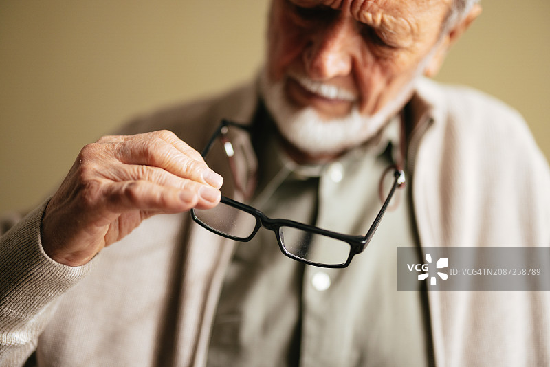 一位拿着眼镜的匿名悲伤老人图片素材