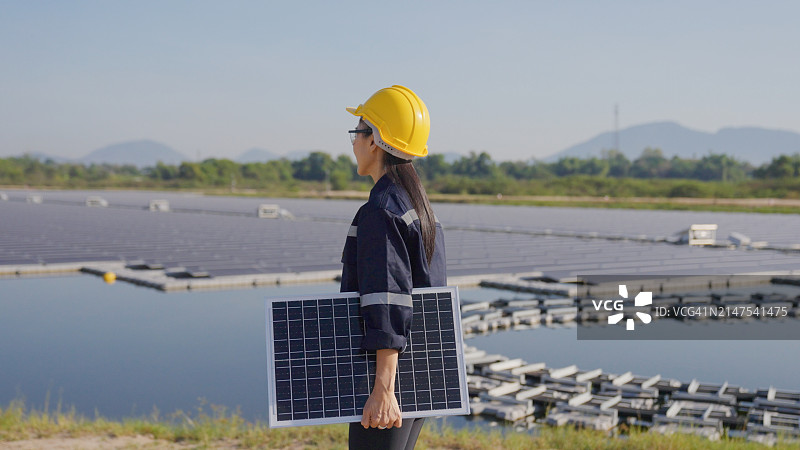 泰国，一名亚洲女工程师在一个浮动太阳能农场现场处理太阳能电池板。图片素材