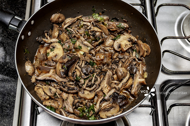 从上面看，一种混合的新鲜蘑菇正在煎锅里加热。开放的计划。图片素材