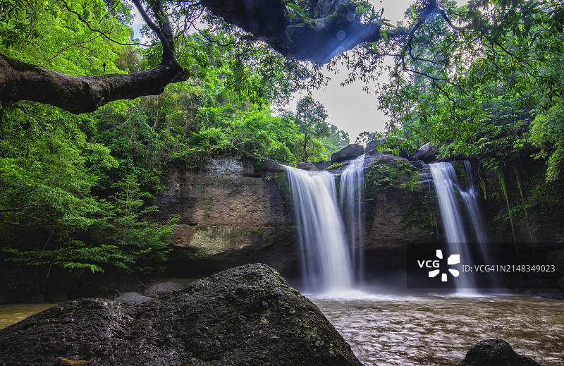 令人惊叹的看不见的瀑布，有洞穴和自然树木的框架，在野外的水和岩石上的倒影，在泰国那空叻差玛的考艾国家公园(联合国教科文组织)的Haew Suwat瀑布，傍晚前的美丽日落图片素材