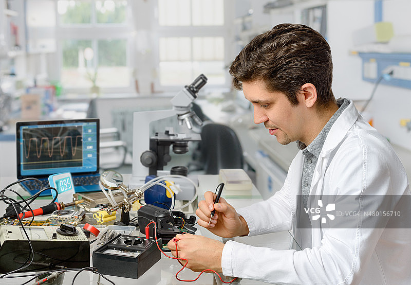 年轻男性技术人员或工程师正在修理电子设备图片素材
