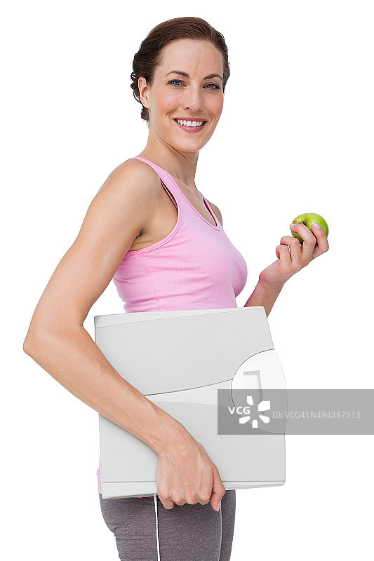 一个带着体重秤和苹果的年轻女人的肖像图片素材