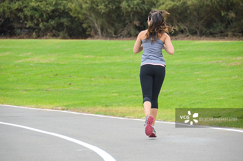 运动健将的年轻女子在跑道上奔跑图片素材