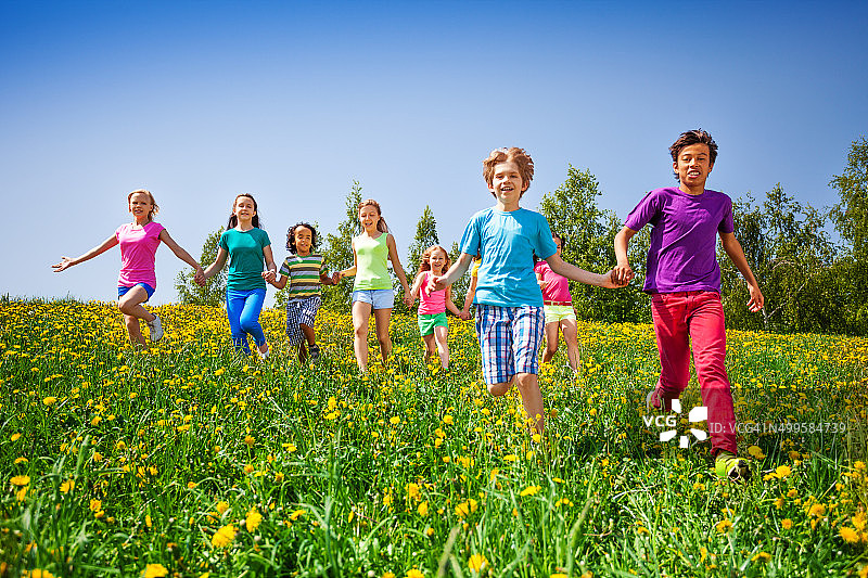 孩子们手牵着手在绿色草地上奔跑图片素材