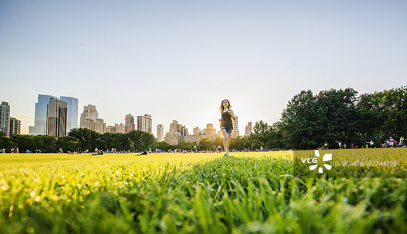 女孩在中央公园曼哈顿天际线前奔跑图片素材