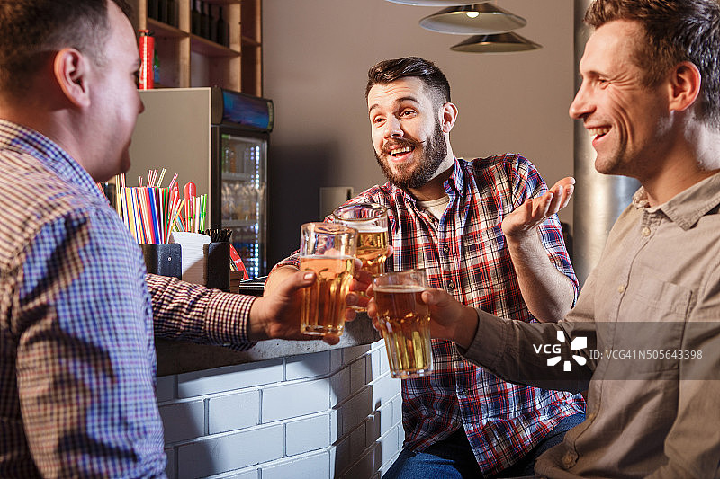 快乐的朋友在酒吧的柜台喝啤酒图片素材