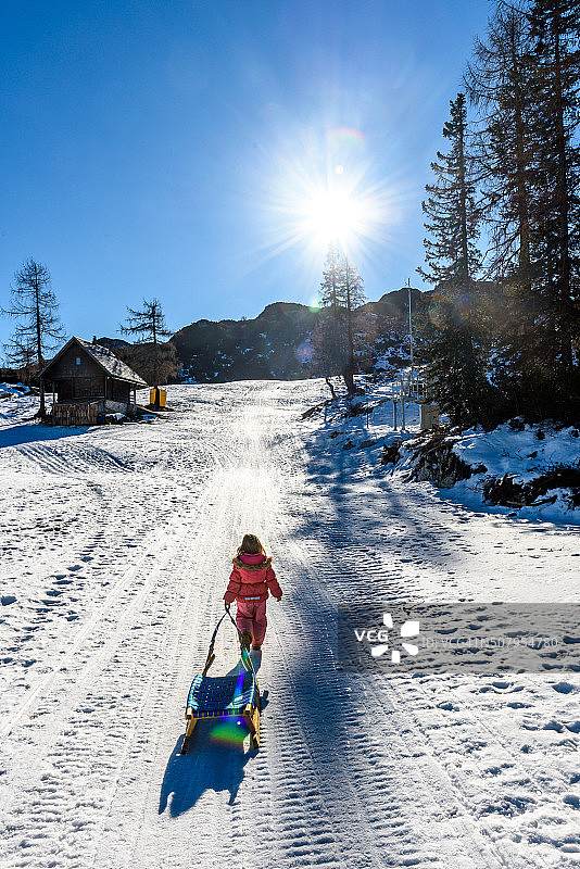 滑雪场的女孩正拉着雪撬，穿着冬天的衣服图片素材