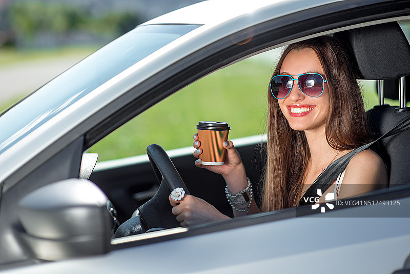 年轻女子一边开车一边喝咖啡图片素材