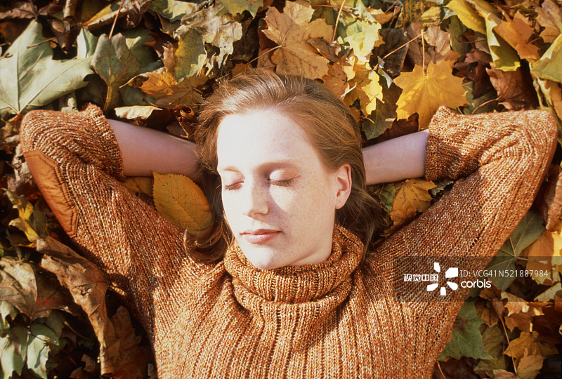 年轻女子躺在树叶中图片素材