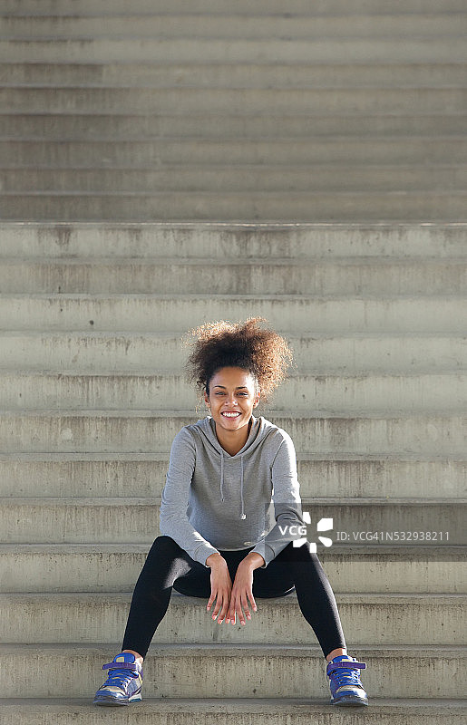 快乐的年轻女运动员坐在户外的台阶上图片素材