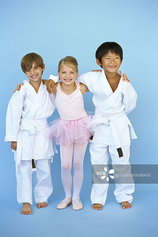 一个穿着芭蕾裙的女孩和两个穿着柔道制服的男孩微笑的肖像图片素材