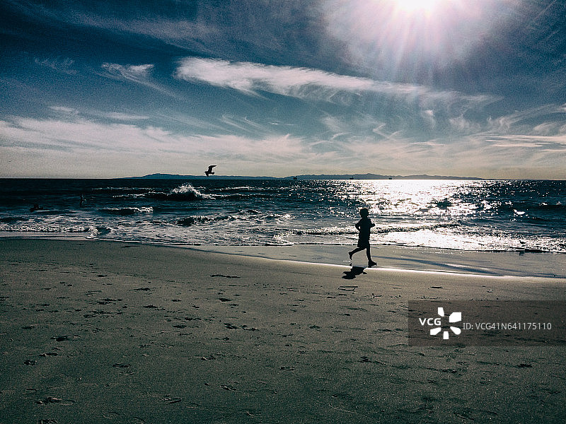 快乐的大自然男孩在海滩上奔跑图片素材