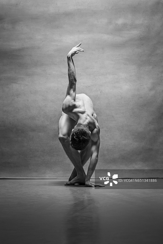 男芭蕾舞者在灰色背景下摆姿势图片素材