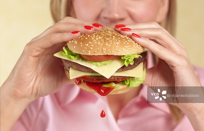 女人咬着汉堡，番茄酱滴着图片素材