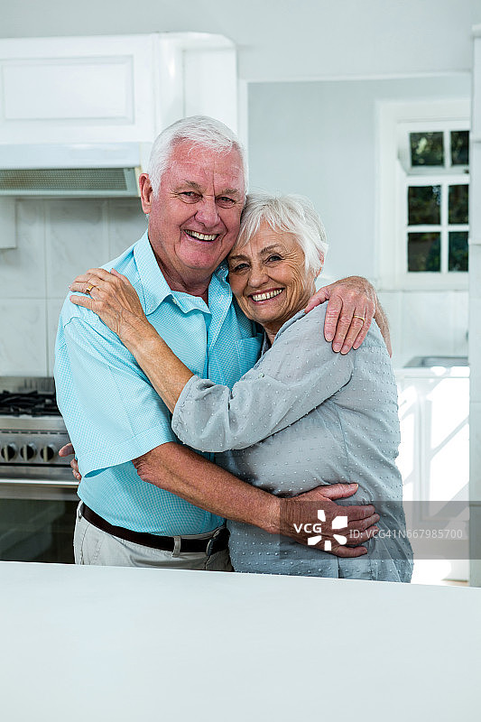 快乐的老夫妇在厨房拥抱图片素材