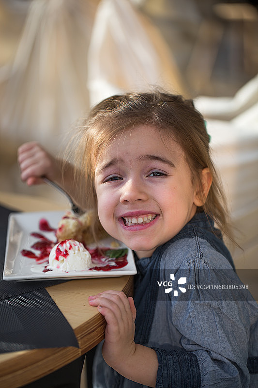 咖啡馆里的小女孩吃着甜点图片素材