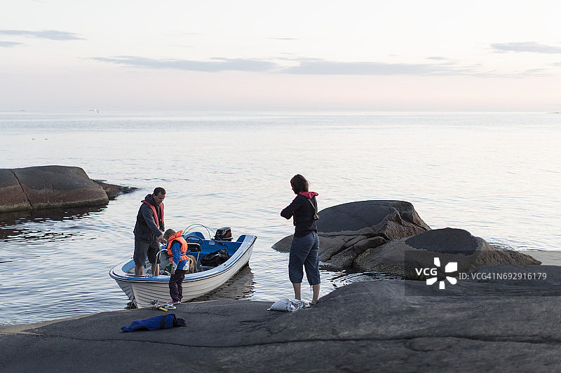一家人和摩托艇站在波罗的海的天空在日落图片素材