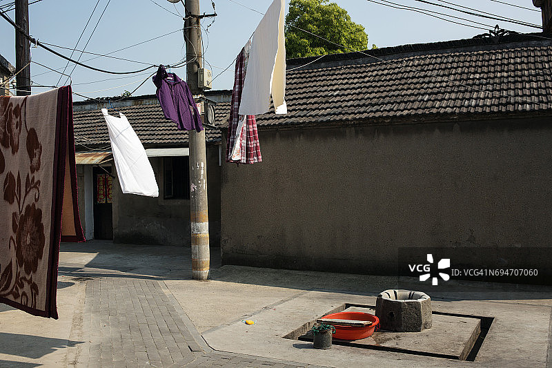 在中国扬州的胡同里，毯子和衣服挂在晾衣绳上图片素材