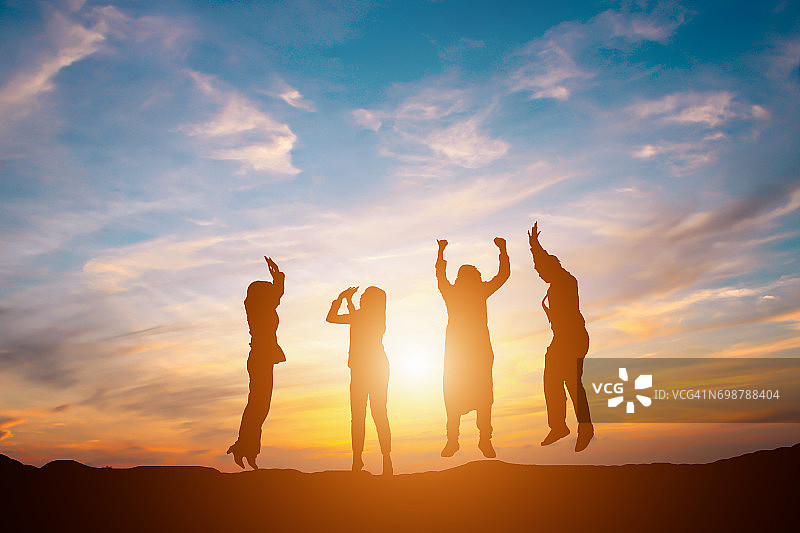 剪影快乐的企业团队在日落天空高手背景为企业团队合作的概念图片素材