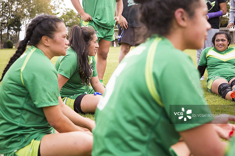 女橄榄球运动员坐在球场边进行团队谈话图片素材