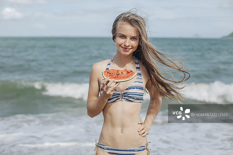 一个白人女人在海滩上吃西瓜图片素材