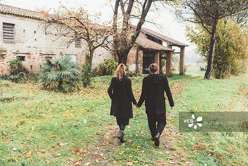 夫妇散步的旧农场建筑的后视图图片素材