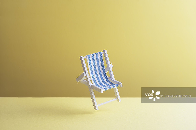 一张沙滩椅悬浮在黄色地面前的空中，3D渲染图片素材