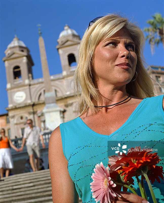 一个女人拿着花站在罗马教堂前图片素材