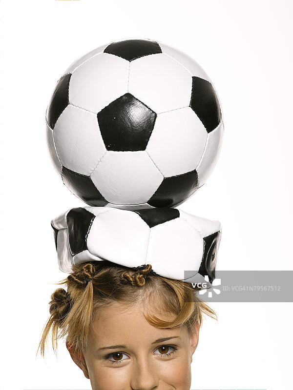 女孩用头顶着足球保持平衡图片素材