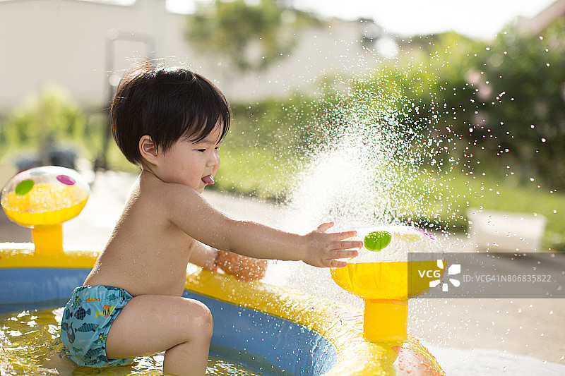 亚洲幼童在充气泳池玩水。图片素材