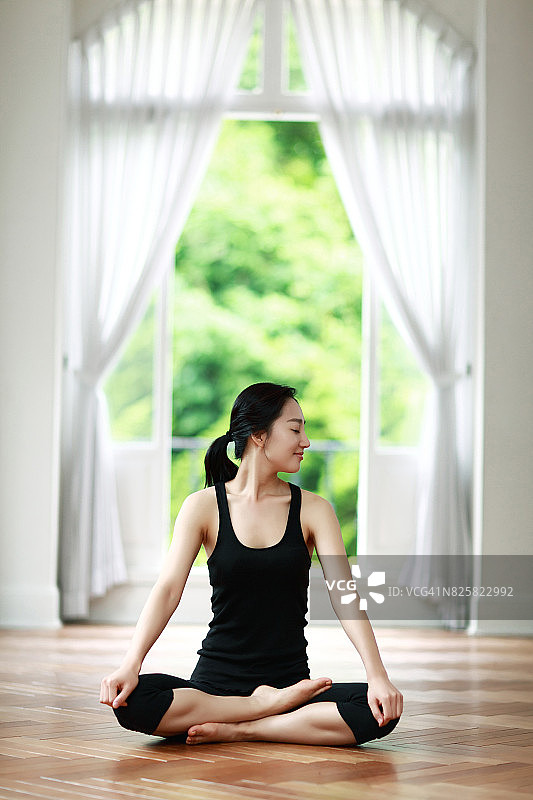 在客厅里做瑜伽的女人图片素材