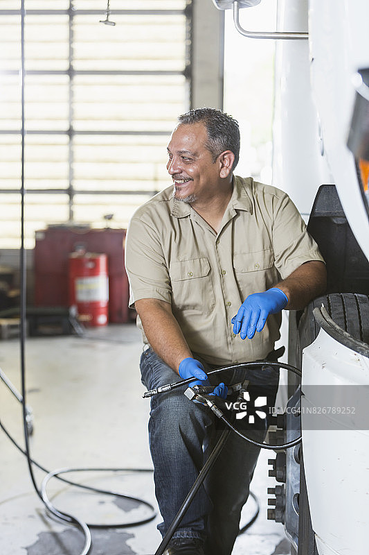 成熟的男子在汽车修理厂工作的半卡车图片素材