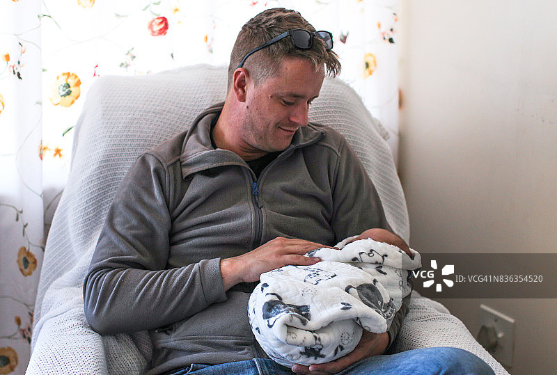 一位父亲在医院里抱着他刚出生的男婴。图片素材