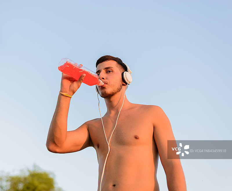 英俊的运动员在训练后喝水。图片素材