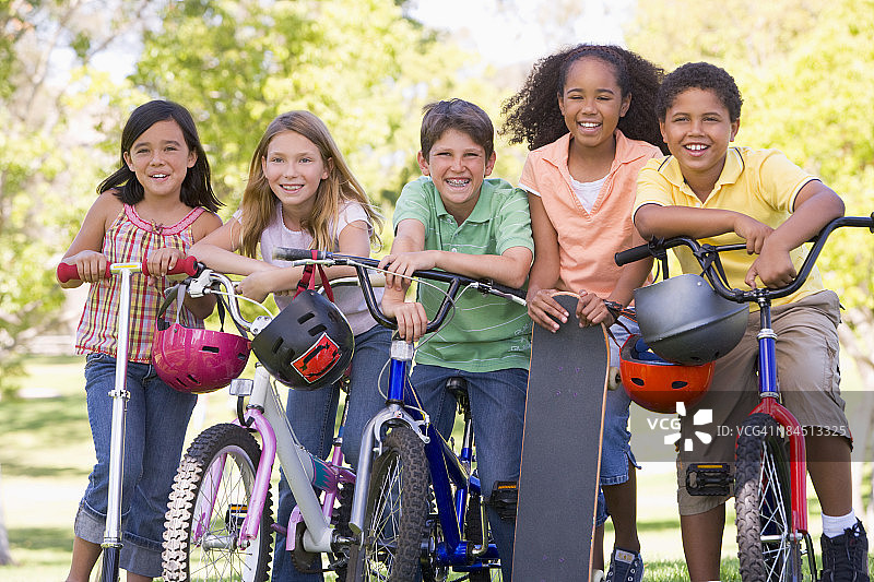 五个年轻的朋友带着自行车、滑板和滑板在户外微笑图片素材