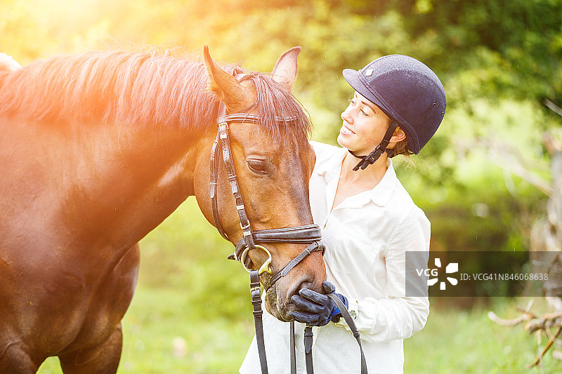 年轻漂亮的女骑手戴着头盔骑着马图片素材