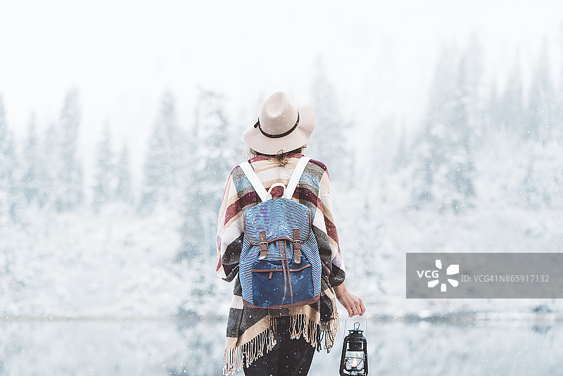 年轻的女旅人拿着油灯在野外享受初雪图片素材
