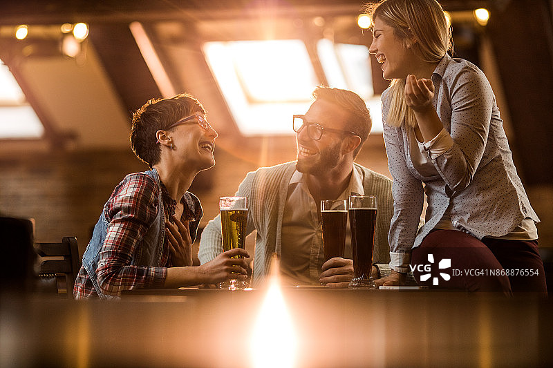 年轻快乐的人们下班后去酒吧喝啤酒聊天。图片素材