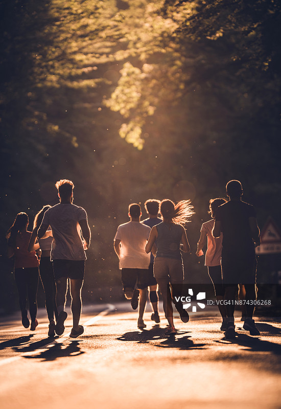 后视图的一组运动员跑马拉松在日落。图片素材