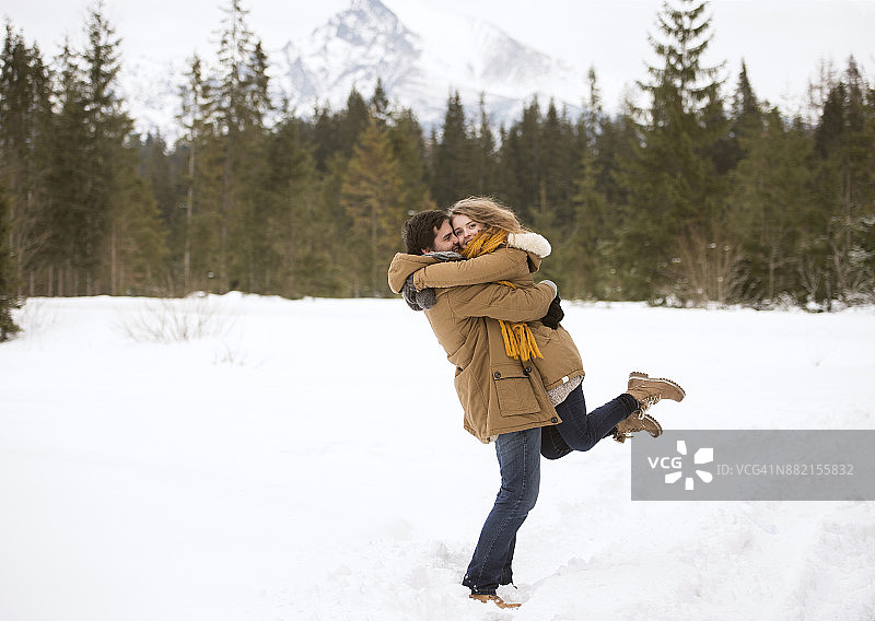 幸福的年轻夫妇在冰雪覆盖的冬季景观图片素材